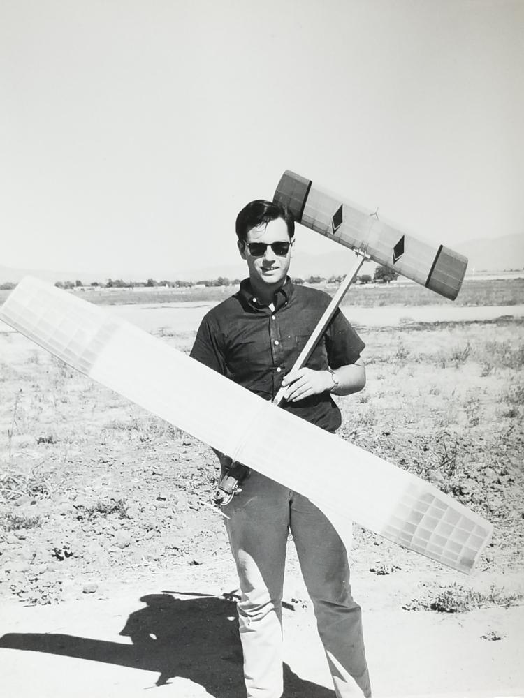 Man holding a large model airplane outdoors.