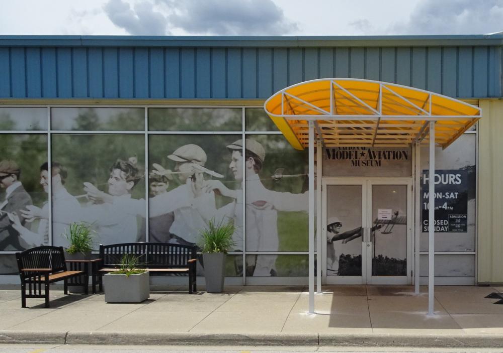 Entrance to Model Aviation Museum with benches and large vintage photo.