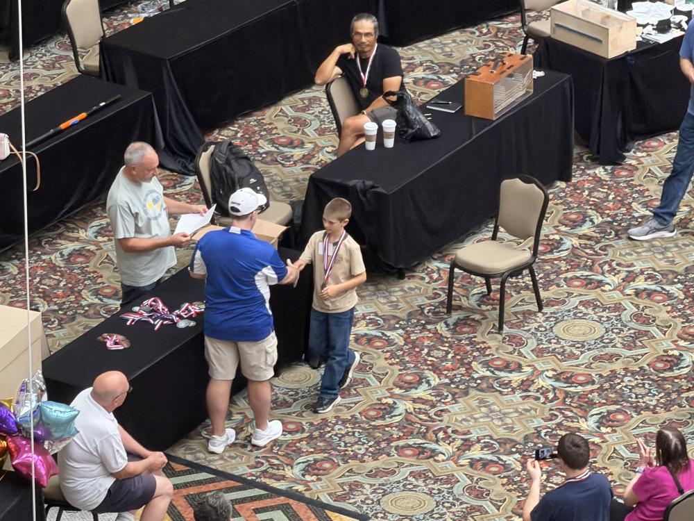Award ceremony in a conference room with a boy receiving a medal.