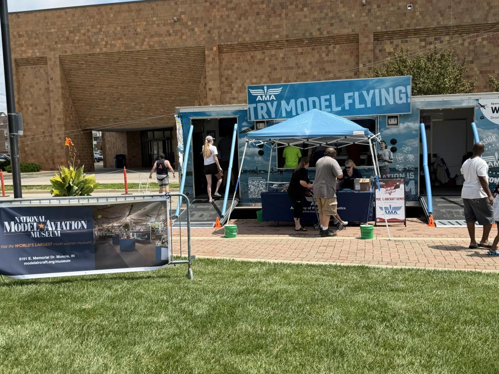 People gathered around a "Try Model Flying" booth outdoors.