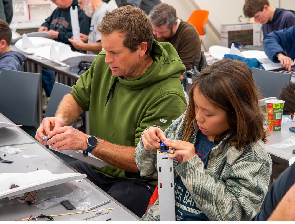 Man and child assembling models at a workshop.