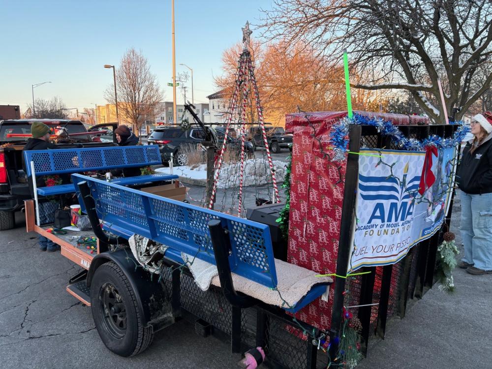 Holiday-themed parade float with blue benches and festive decorations.