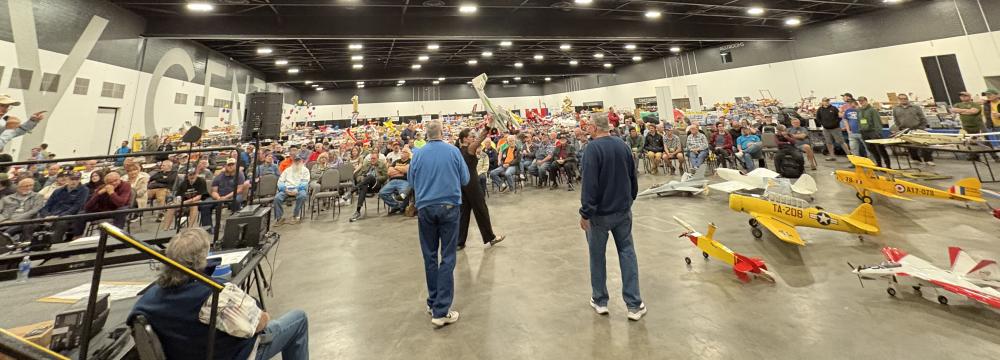 Model airplanes on display in a crowded exhibition hall.