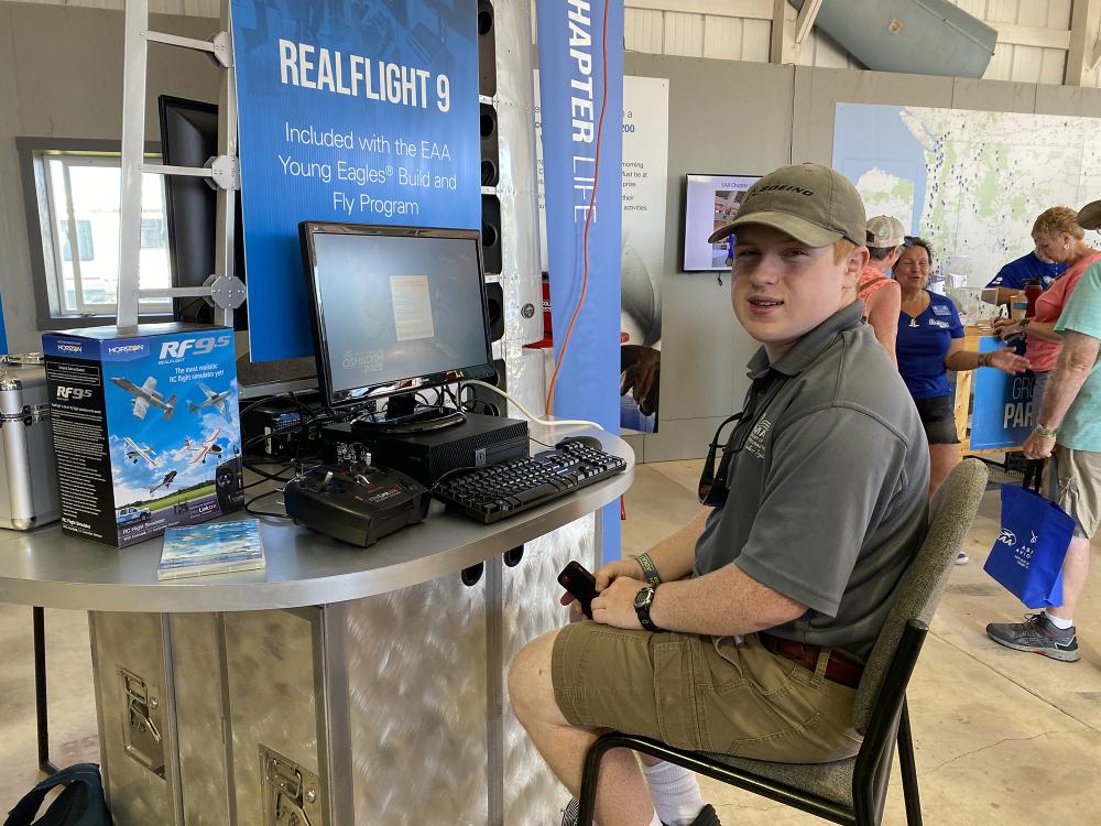 Man sitting at a booth with flight simulation equipment.
