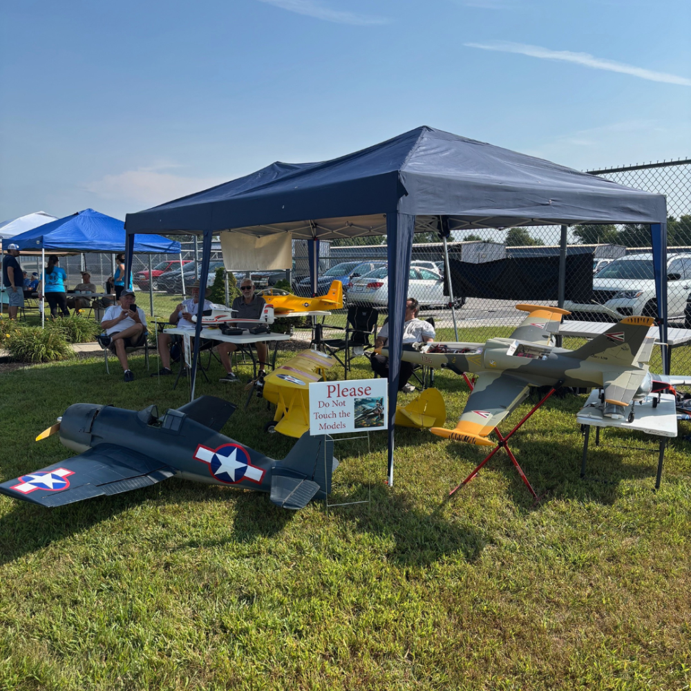 Model planes displayed under a canopy at an outdoor event.