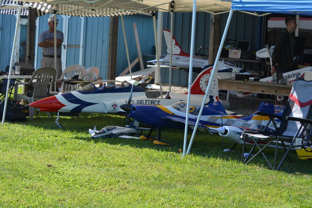 Model aircraft displayed under tents on grass.