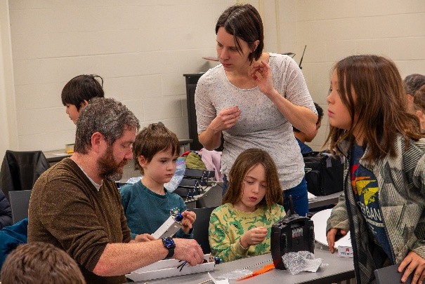 Adults and children engaged in a group activity at a table indoors.