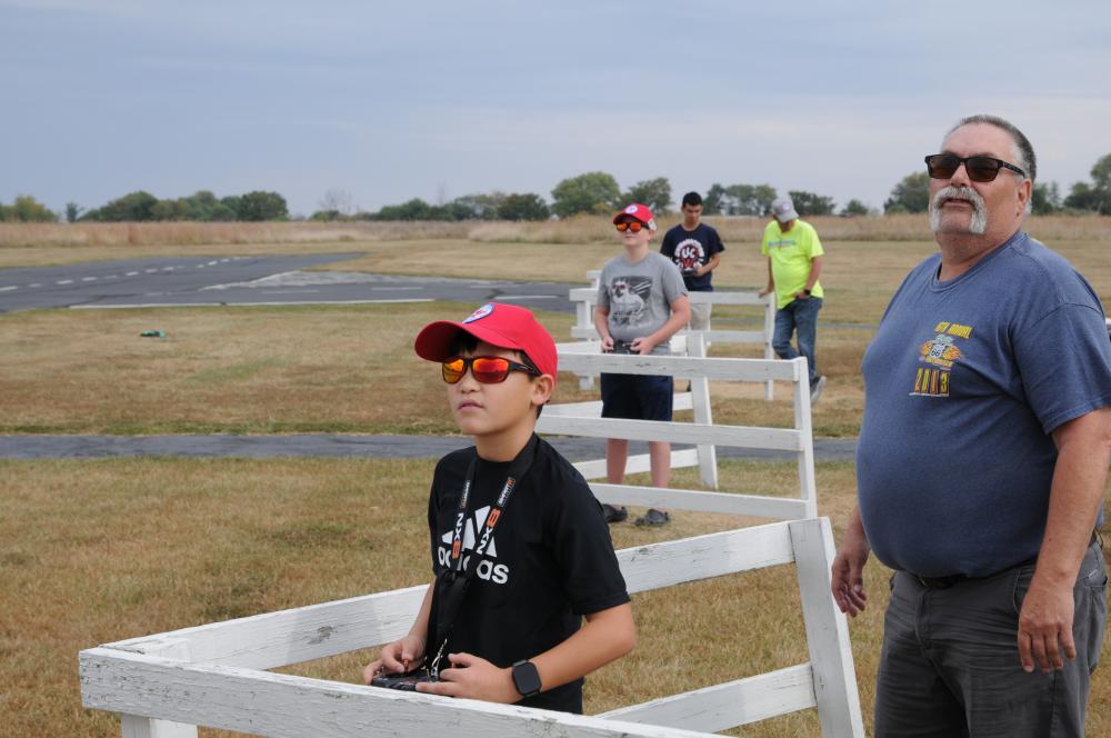 People outdoors flying remote-controlled planes on a field.