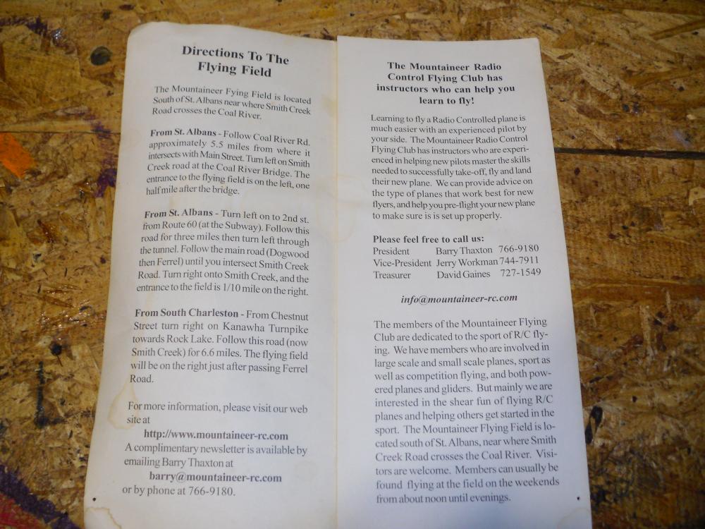 Paper with text instructions and contact details, on a wooden surface.