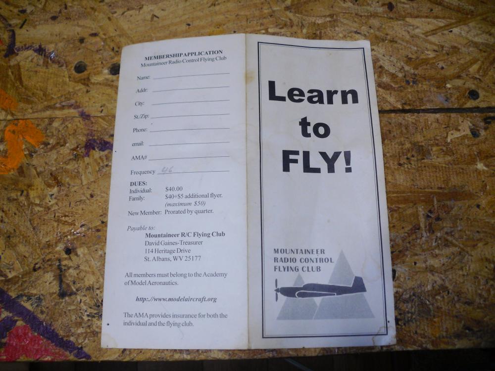Brochure on wooden surface, "Learn to FLY!" text with plane graphic.