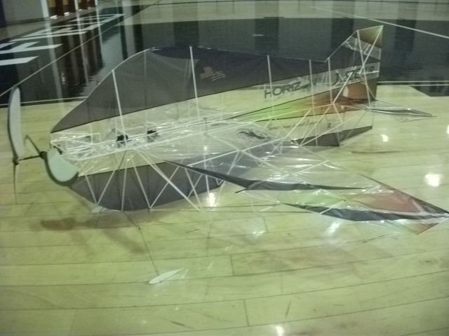 Transparent model airplane on a gymnasium floor.
