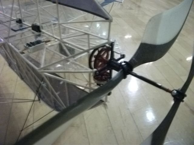 Model airplane propeller and frame on wooden floor.