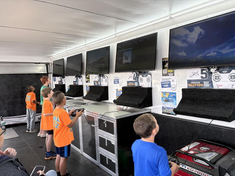 Children playing video games on multiple screens in a gaming trailer.