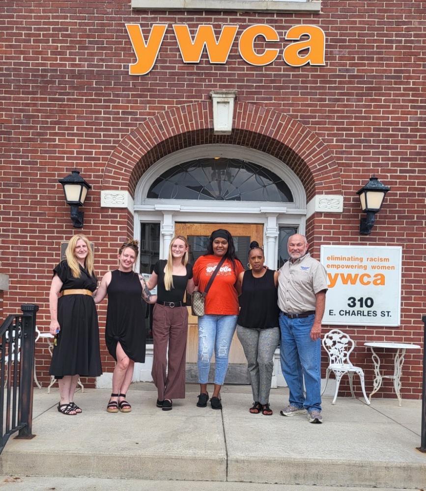 YWCA staff and visitors stand smiling outside a brick building entrance.