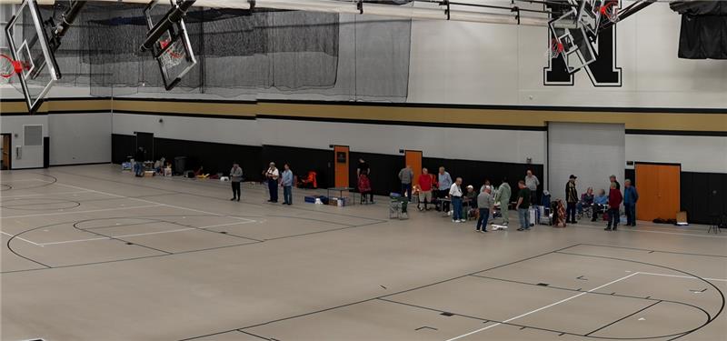 Gym with people lining one wall, basketball hoops overhead.