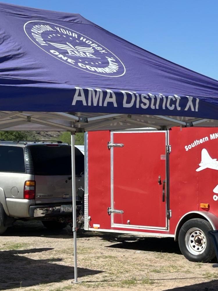 Blue AMA District XI canopy with a red trailer and SUV underneath.