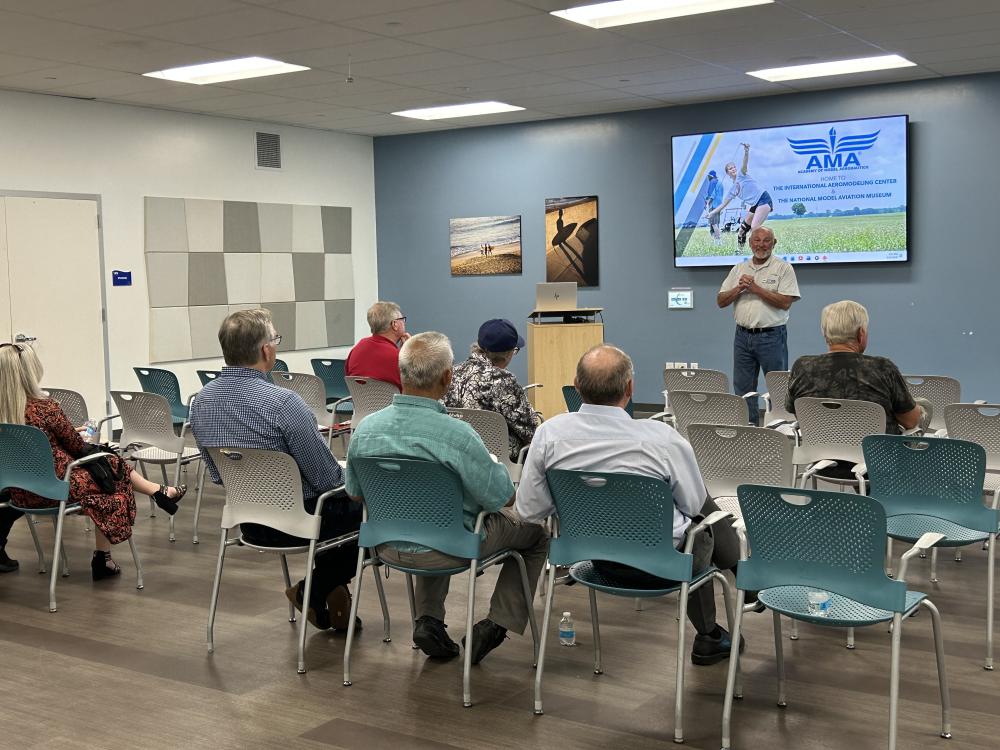 Man speaking to a small audience in a conference room.