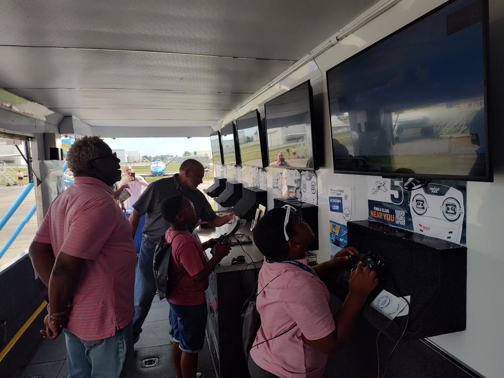 People in a trailer playing video games on large screens.
