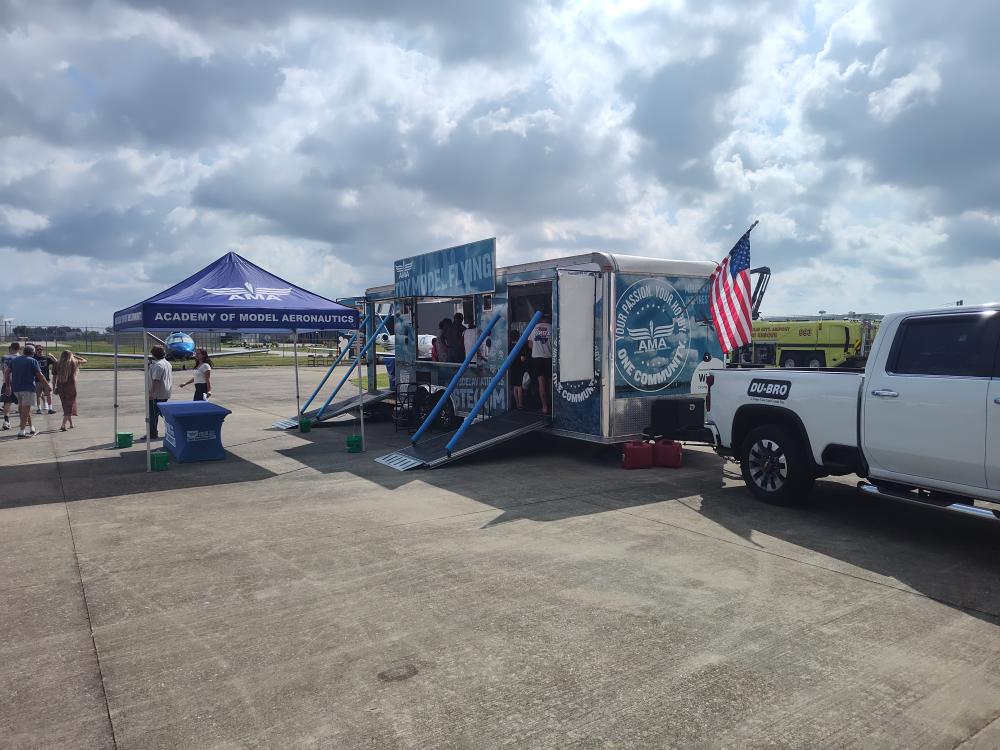 AMA trailer and tent on an airport tarmac under a cloudy sky.
