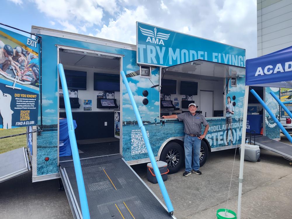 Model aircraft mobile exhibit with ramps and a smiling person.