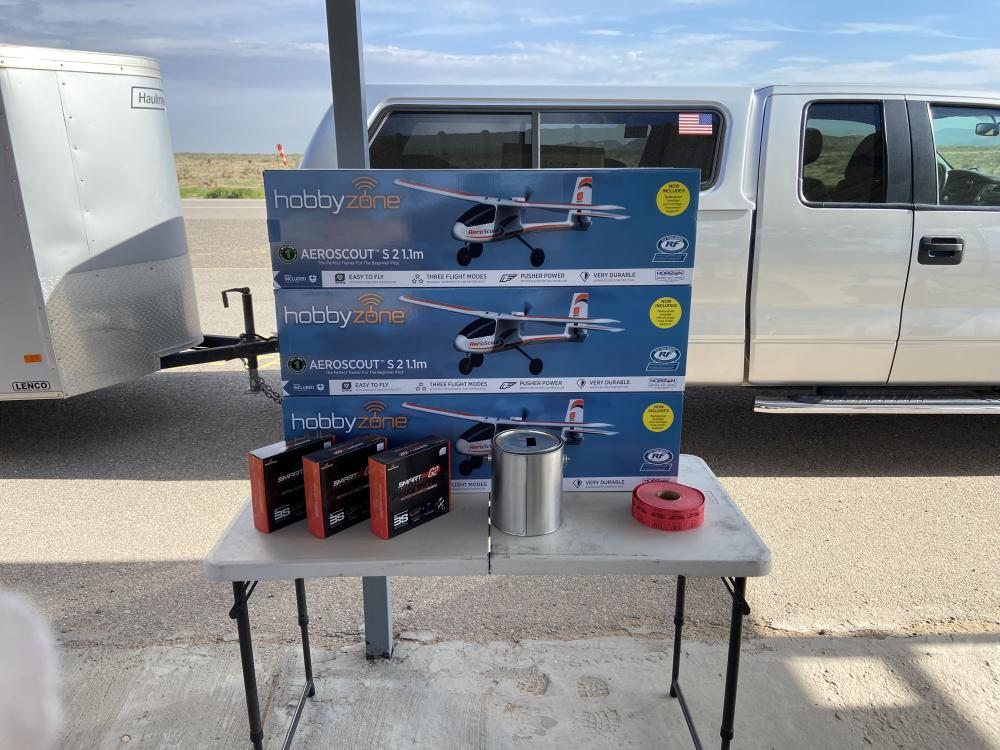 Remote control airplane kits and supplies on a table next to a white truck.