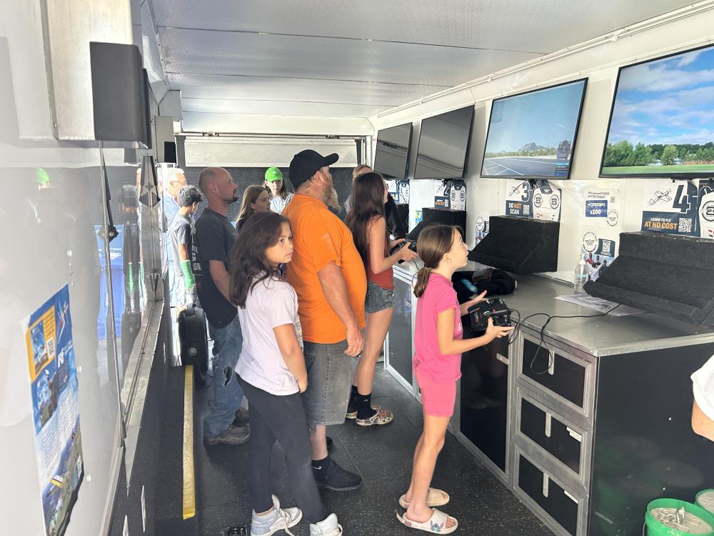 People watching a screen in a trailer, with several children in the foreground.