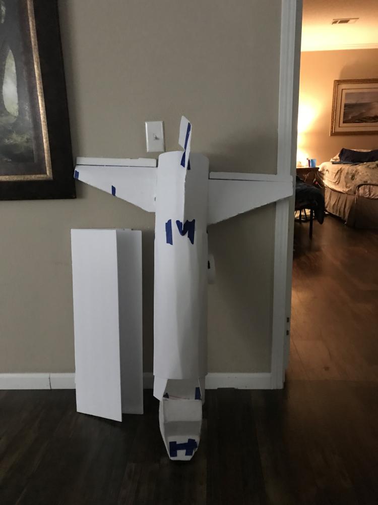 Large paper airplane leaning against a wall in a dimly lit room.