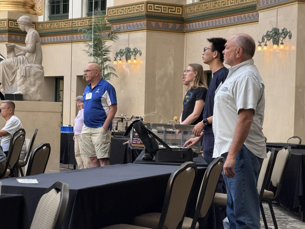People standing inside a large hall with decorative walls and a statue.