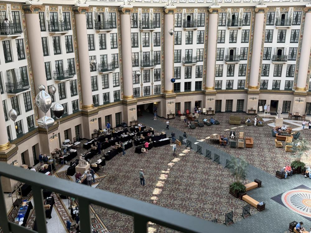 Grand hotel atrium with guests seated at cafe tables below.