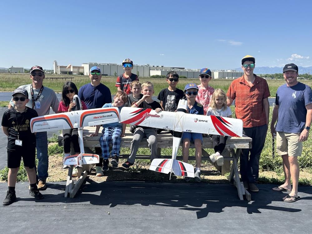 A group of people outdoors with model planes on a sunny day.