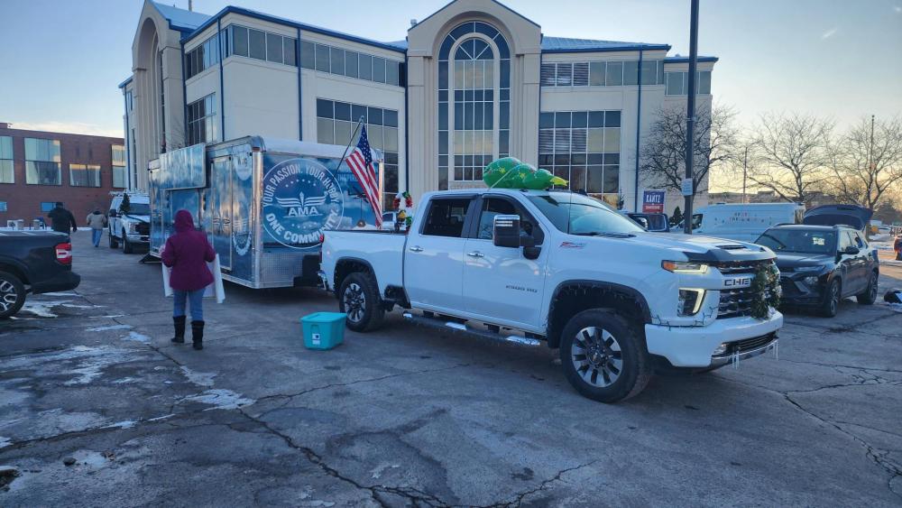 White truck with a blue trailer parked outside a large building.