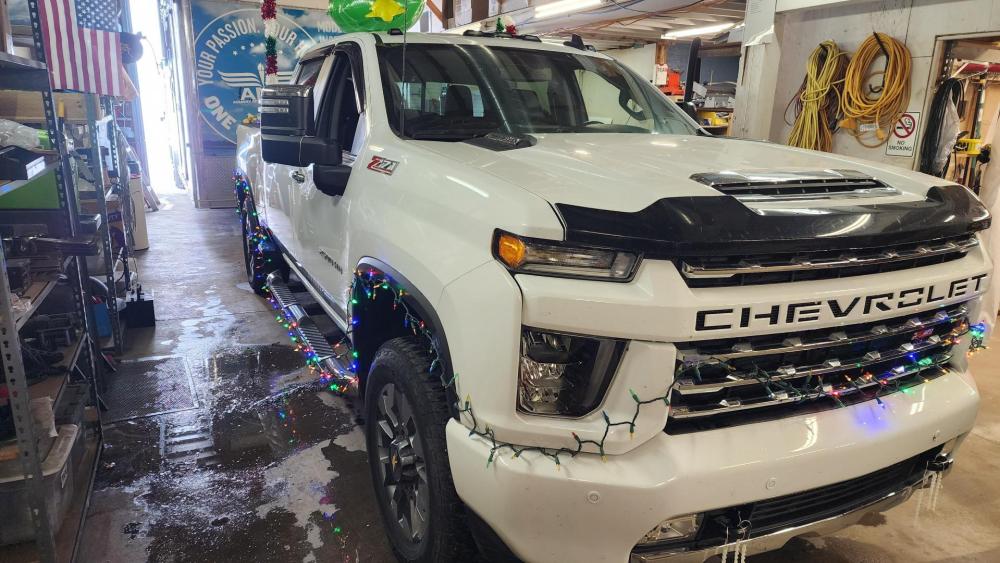 White Chevrolet truck decorated with colorful lights in a garage.