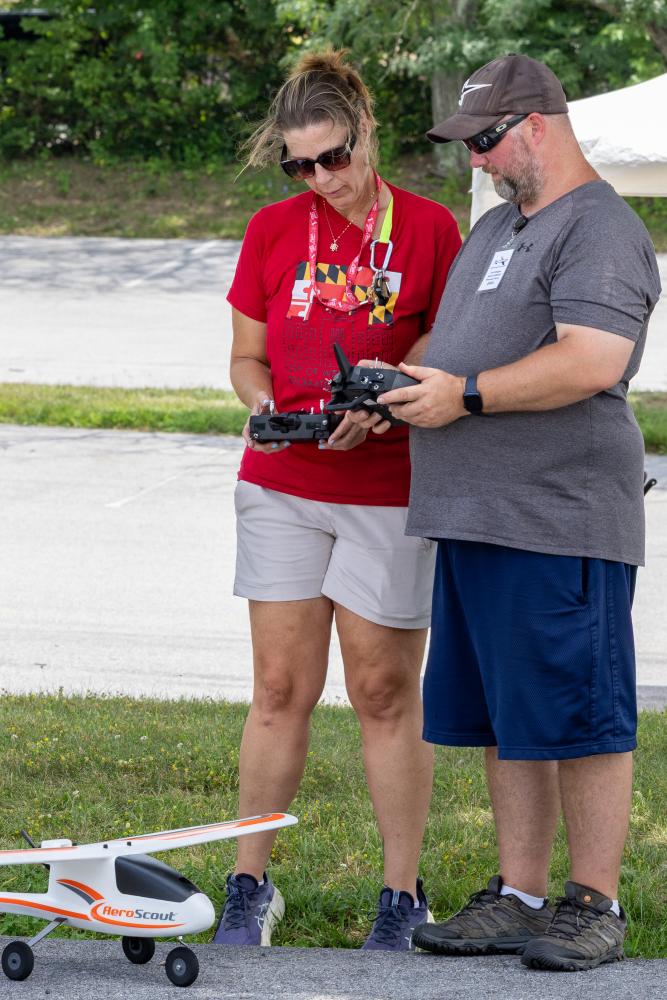Two people operating a remote-controlled plane outdoors.