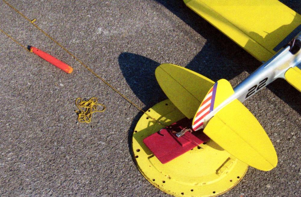 Model airplane with yellow wings on asphalt.