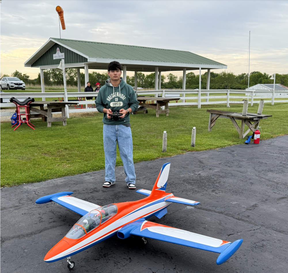 Man controlling large model jet on an airstrip.