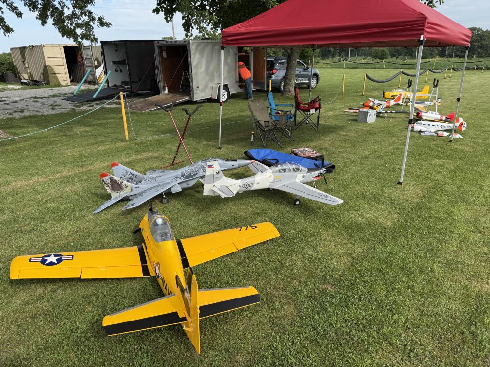 Model aircraft displayed on grass under a red canopy tent.