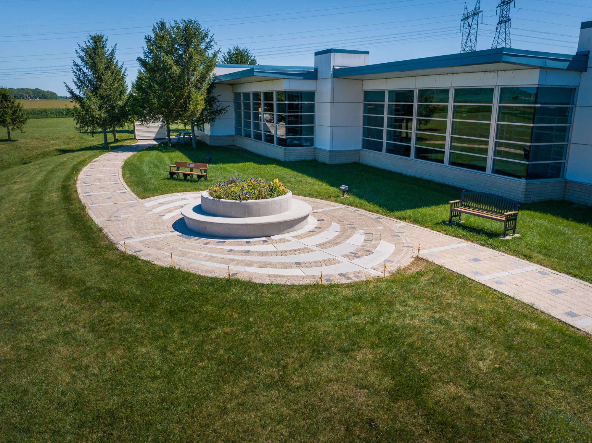 Circular amphitheater with central plant and stone seating, viewed from the side.