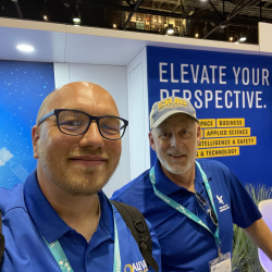 Two people in blue shirts smiling at an event booth.