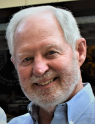 Smiling man with a white beard in a blue shirt.