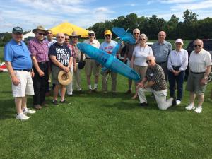 A large group of individuals with one in the middle holding a model aircraft.