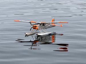 A small orange and gray seaplane floats on calm water.