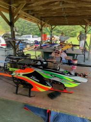 Colorful model helicopters on a table with people in the background.
