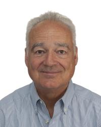Smiling older man with gray hair, wearing a blue striped shirt, against a white background.