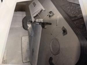 Black and white photo of a cluttered desk with dissected electronics.