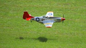Model airplane of a vintage fighter aircraft flying over grass.