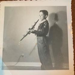 Child holding model airplane, smiling, in uniform, black and white photo.