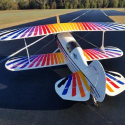 Biplane with colorful striped wings on a runway.