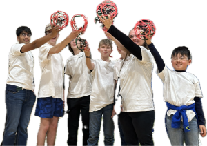 Group of six kids in white shirts holding red geometric models aloft.