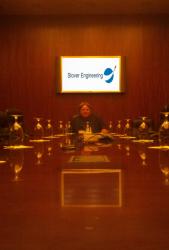Conference room with a person sitting at a long table; Stover Engineering logo on screen.