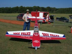 Man outdoors with large remote control model airplane.